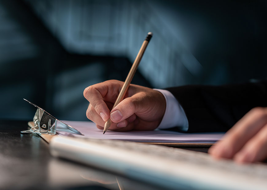 image of man writing with pencil and paper on clipboard