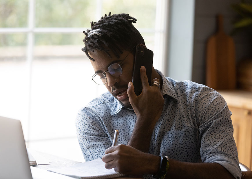 image of man on cell phone and taking notes