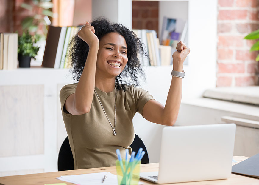 image of woman cheering while looking at laptop