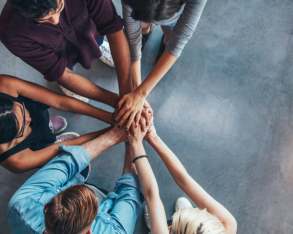 image of group of people putting hand together in middle of circle