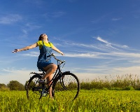 image of woman biking through a field