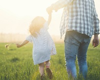 image of man and young girl holding hands in a meadow