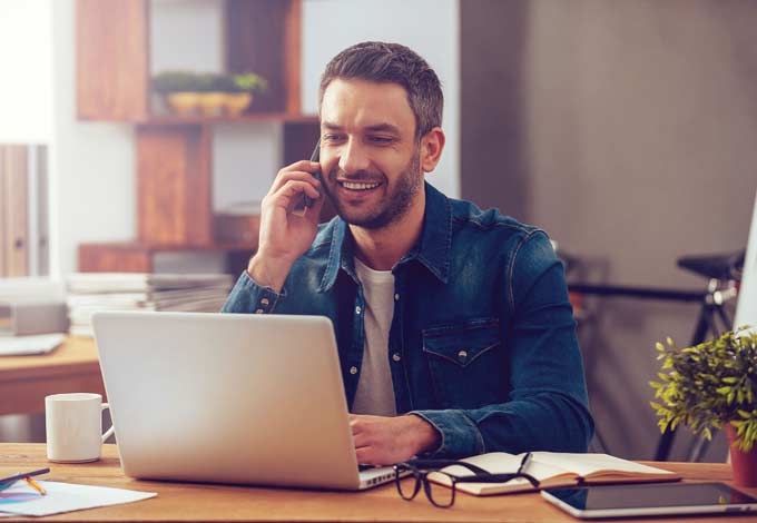 image of man on phone using laptop